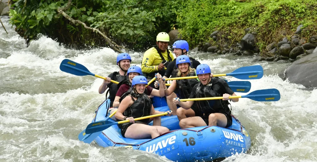 rafting group with guide paddling through river near arenal volcano costa rica