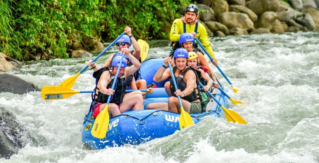 Family and guide navigating whitewater rapids in La Fortuna with Wave Rafting, paddling together through adventure