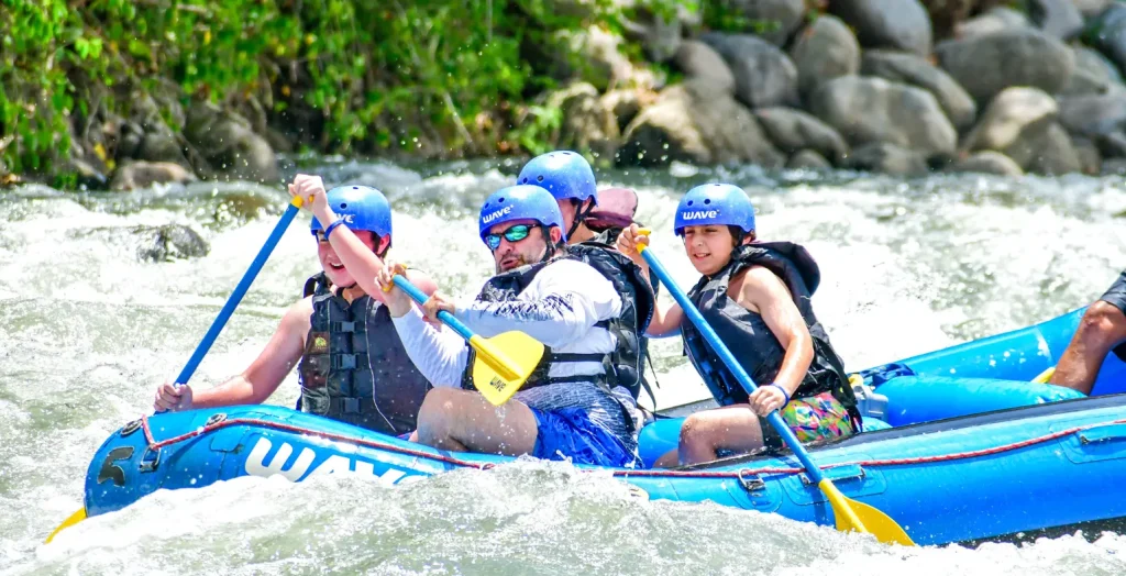 Family paddling through exciting class II-III rapids in La Fortuna with Wave Rafting, sharing laughter and teamwork
