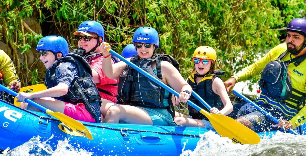 Family rafting together on a blue Wave Expeditions raft in La Fortuna, guided by a professional tour leader